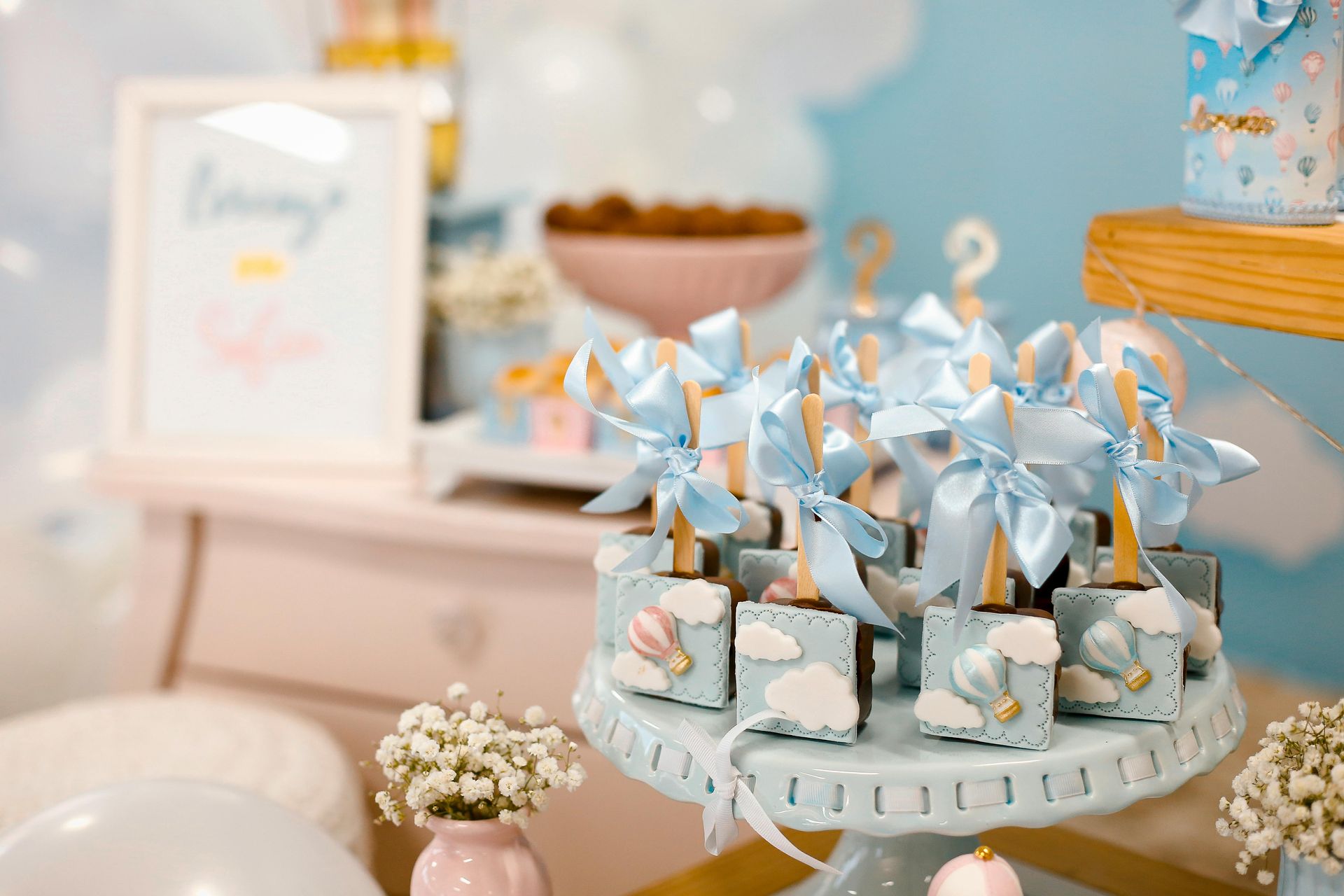 Bord med blå og hvite dekorasjoner, kake og godbiter til en babyshower.