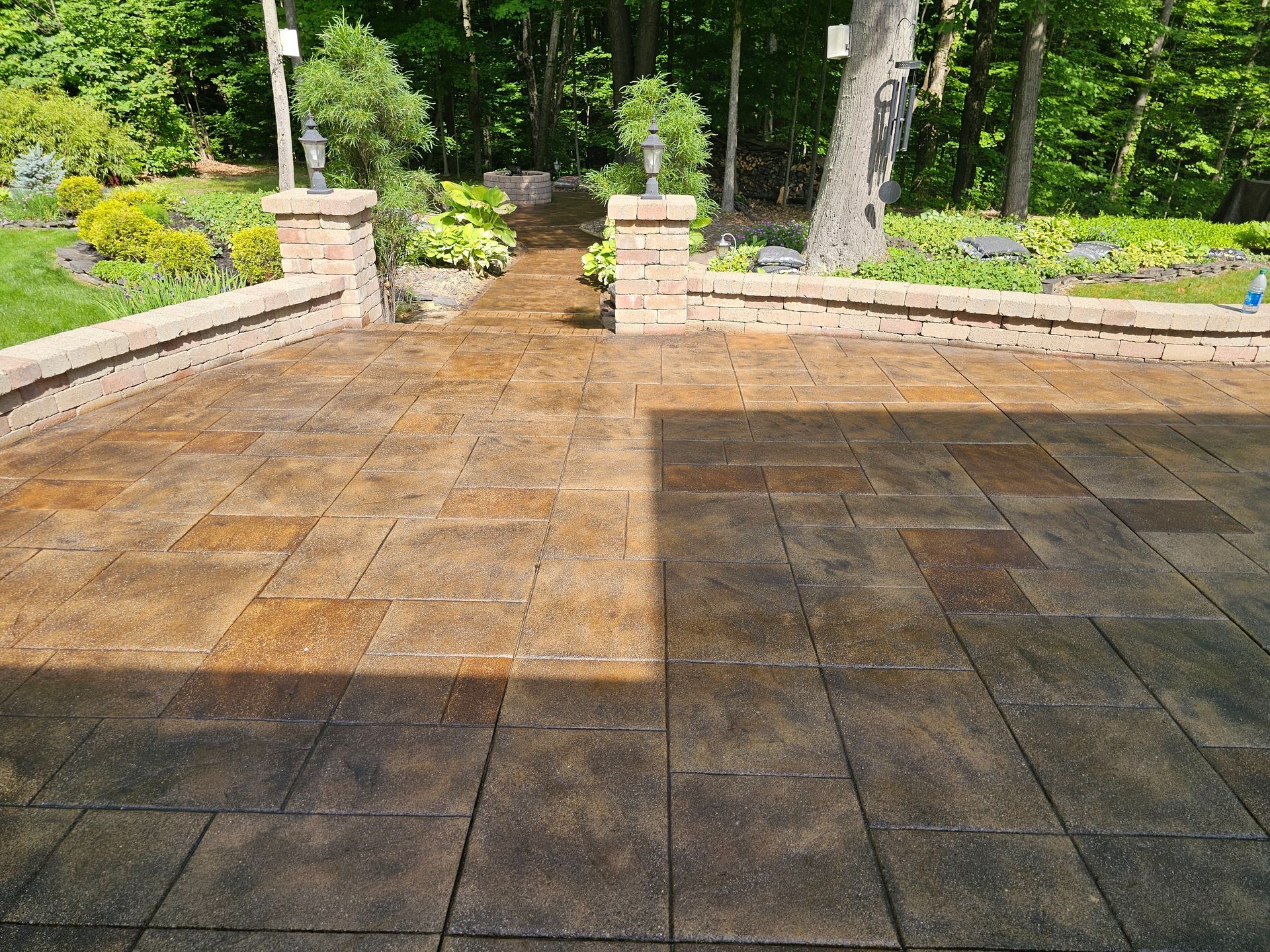 A patio floor during cleaning, showing a stark contrast between a dark, uncleaned side and a lighter, power-washed side.