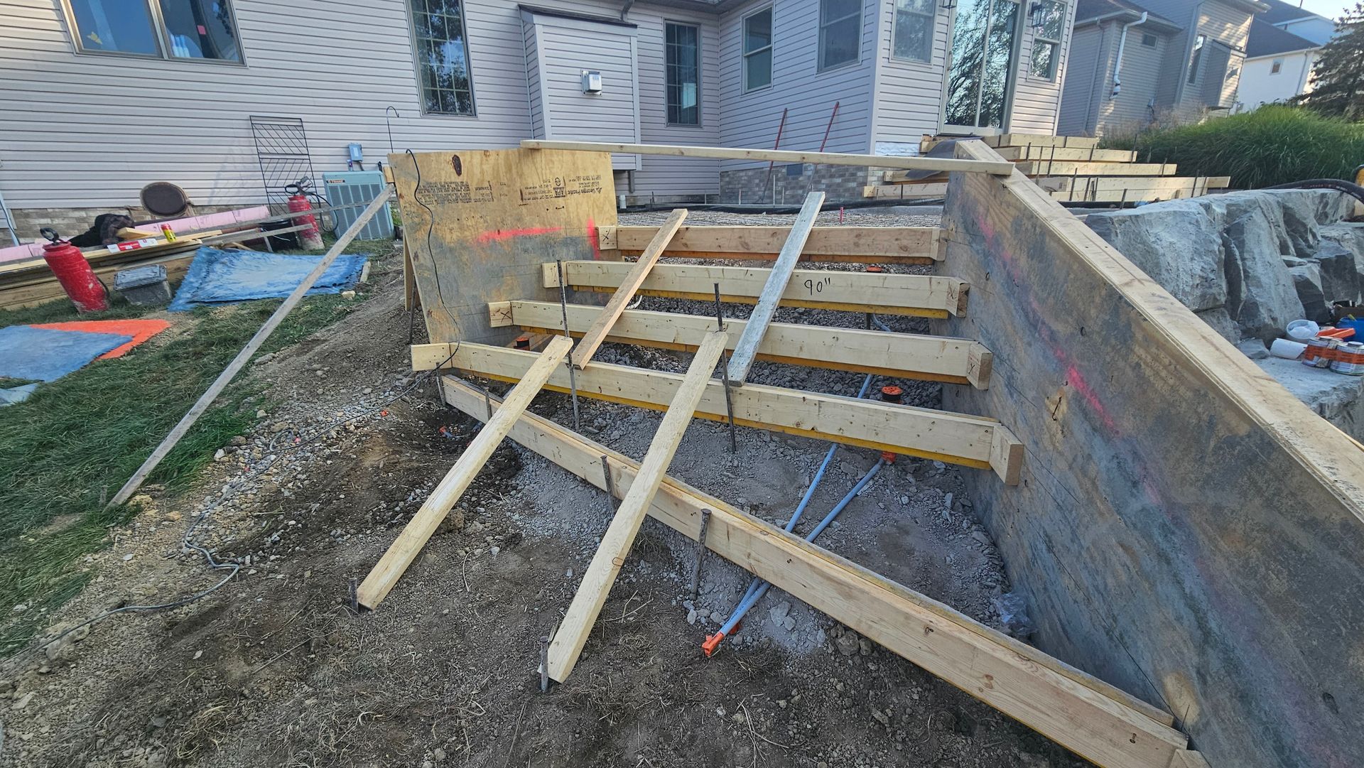 Wooden formwork for a set of concrete steps under construction, set in an outdoor residential yard.