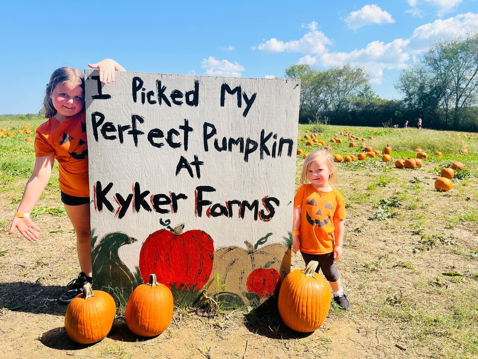 Two children stand by a sign that reads 