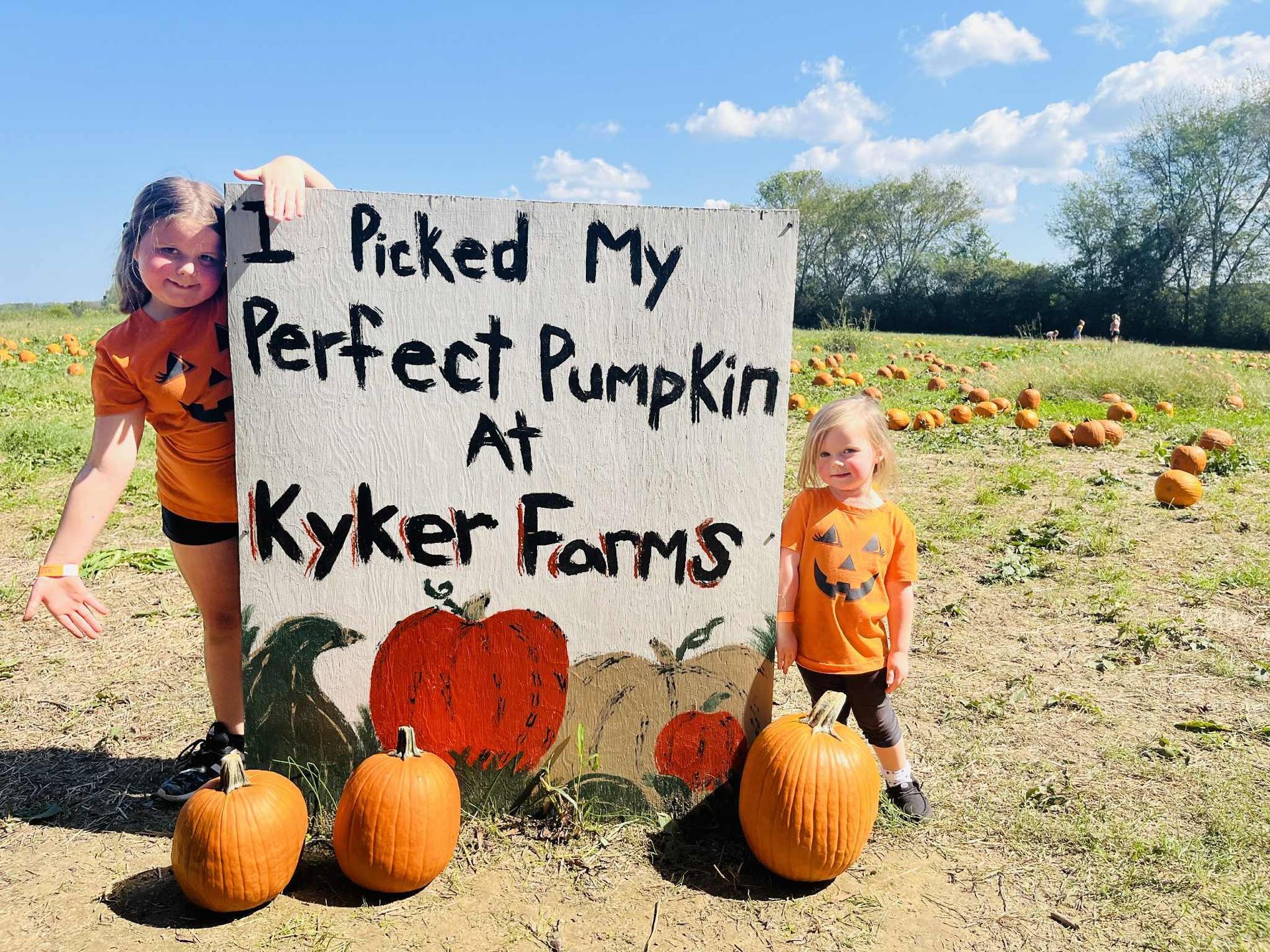 Two children stand beside a painted sign reading 