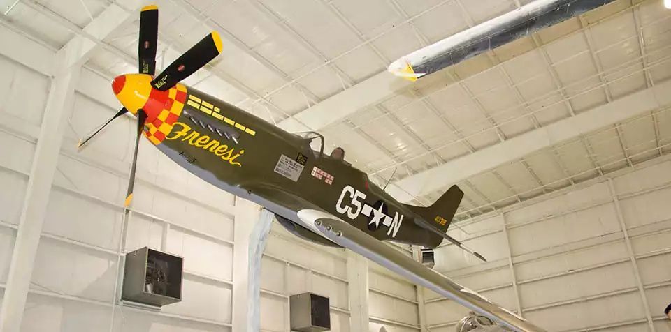 Black-and-yellow aerobatic airplane mounted on a ceiling in an indoor hangar display