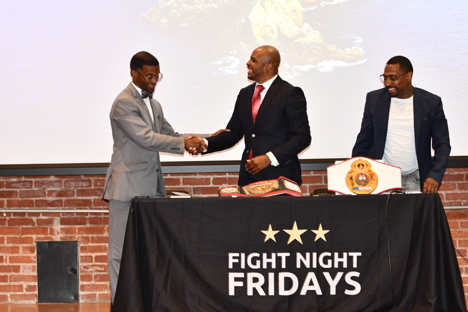 Chris Rivers and two other men shake hands at his book exhibition 