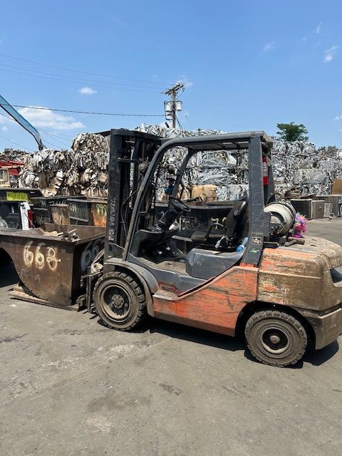 A forklift is parked in front of a pile of scrap metal.