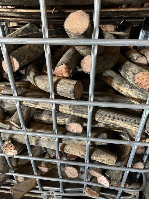 A metal cage filled with wooden logs behind bars.