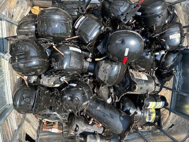 A pile of black plastic containers sitting on top of each other on a wooden table.
