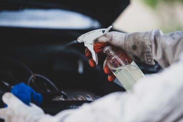 Une personne nettoie une voiture avec un flacon pulvérisateur.