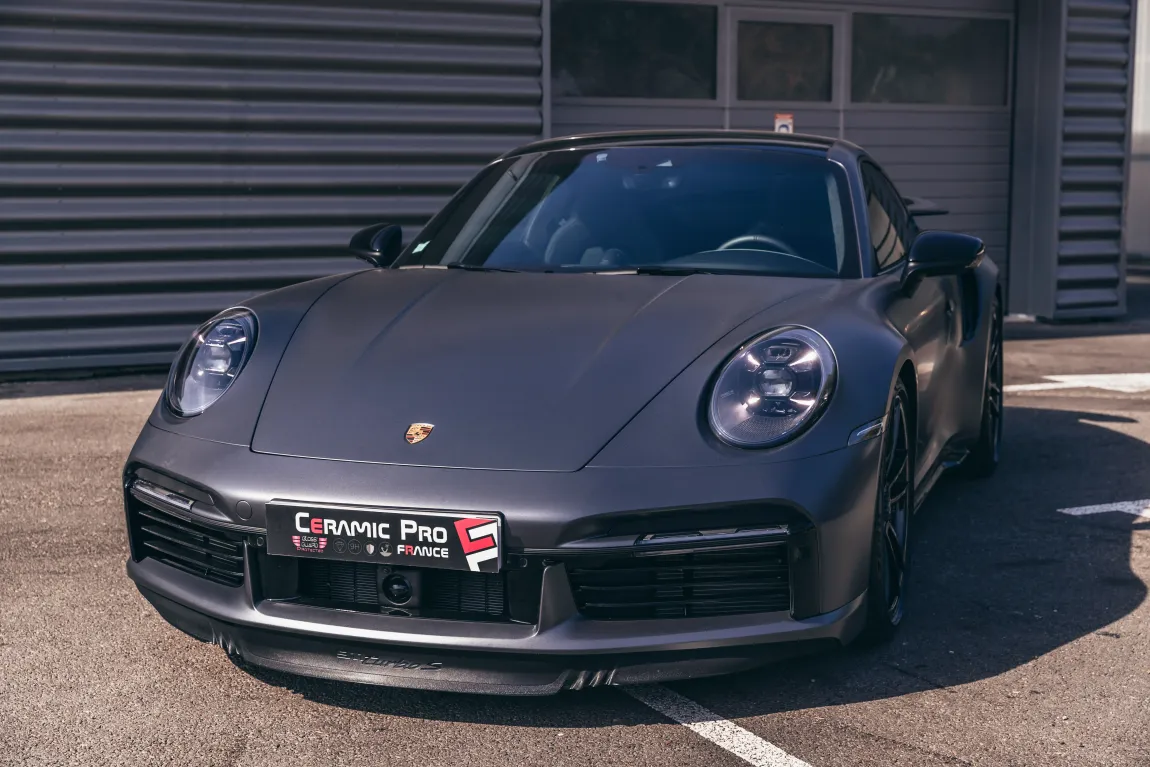 Une porsche 911 turbo s grise est garée dans un parking.