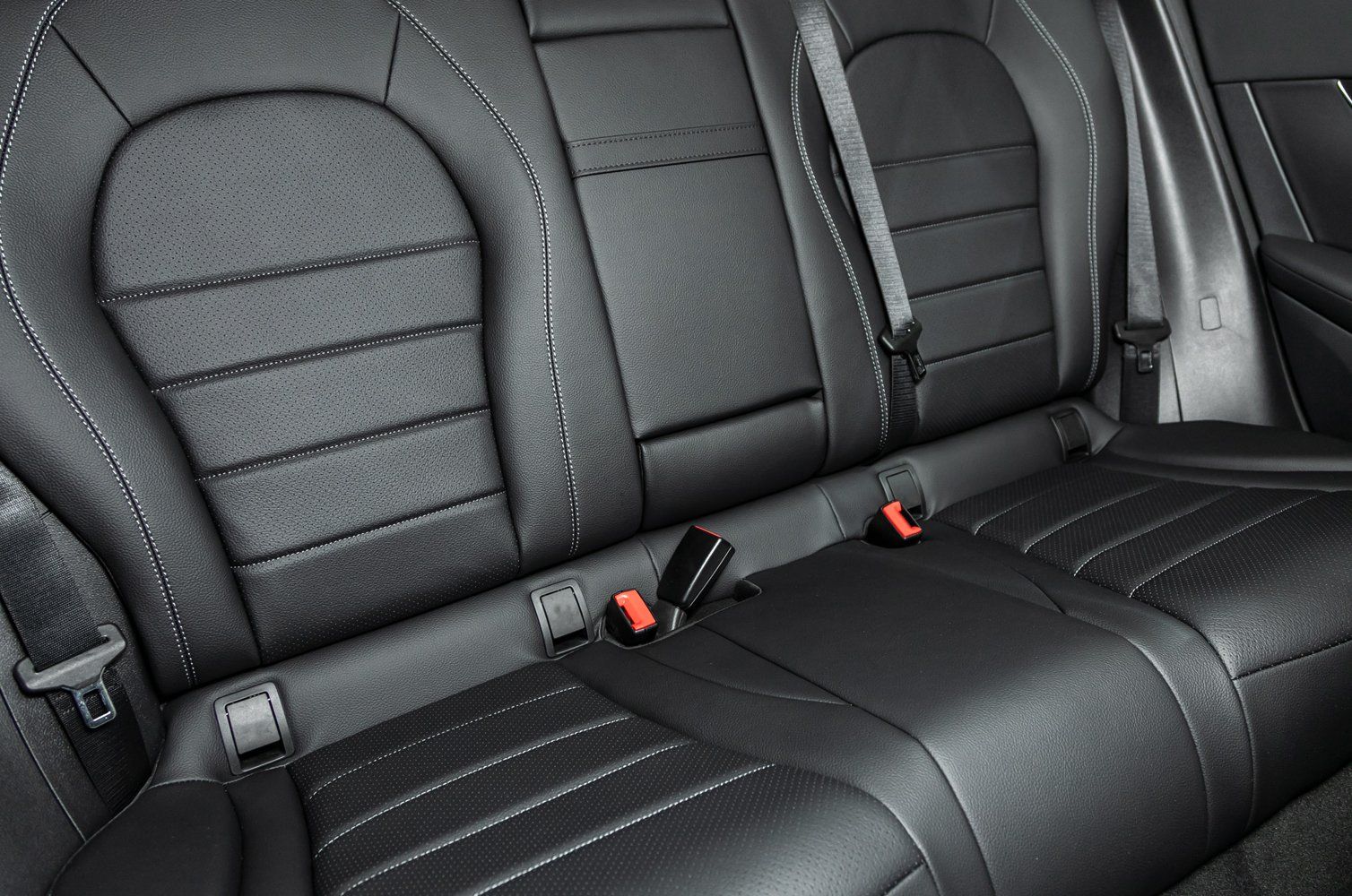 Un gros plan de la banquette arrière d'une voiture avec ceintures de sécurité.