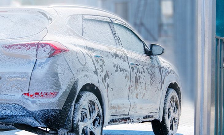Une voiture est recouverte de mousse dans un lave-auto.
