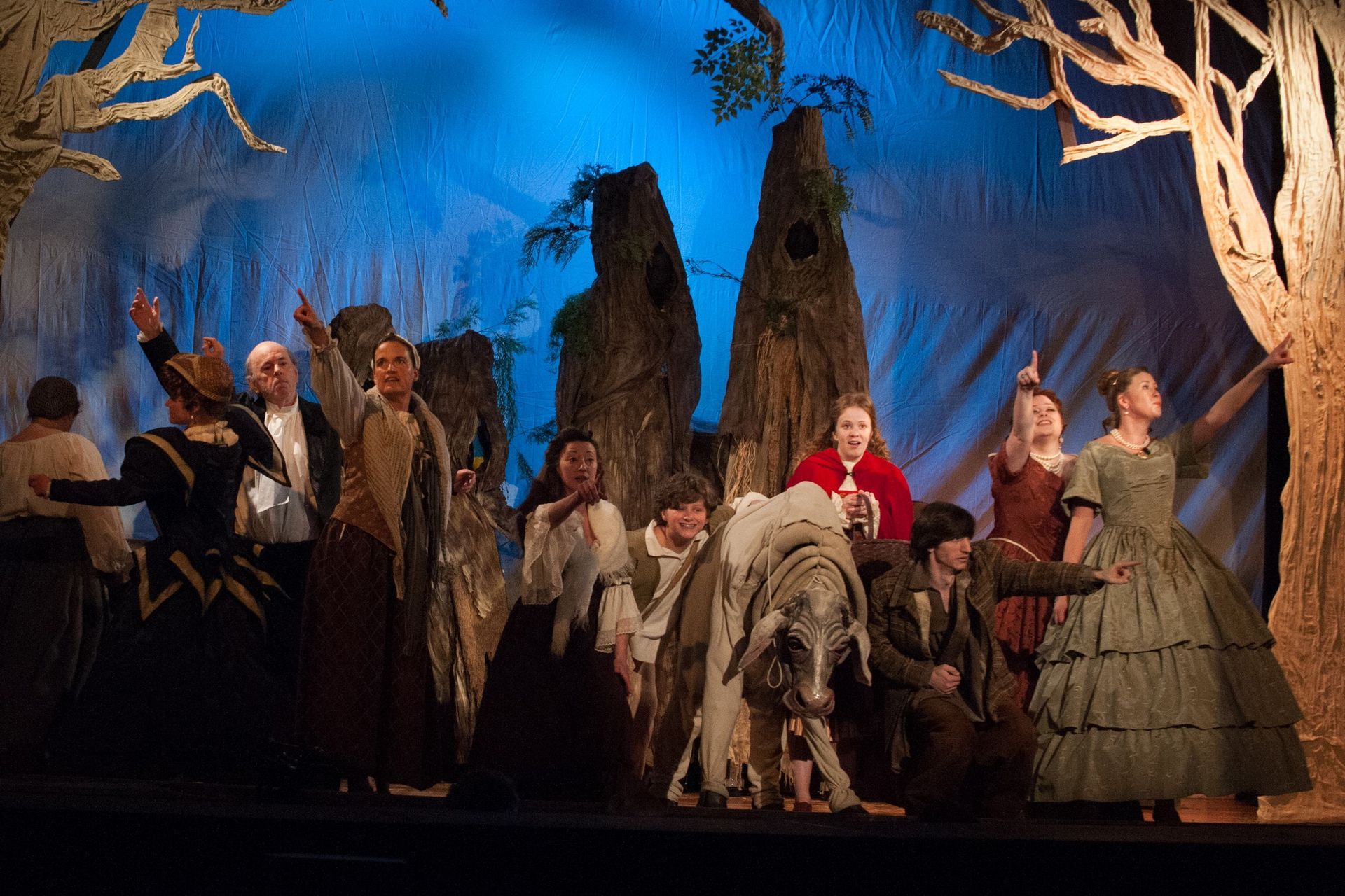 A group of people are standing on a stage with trees in the background.