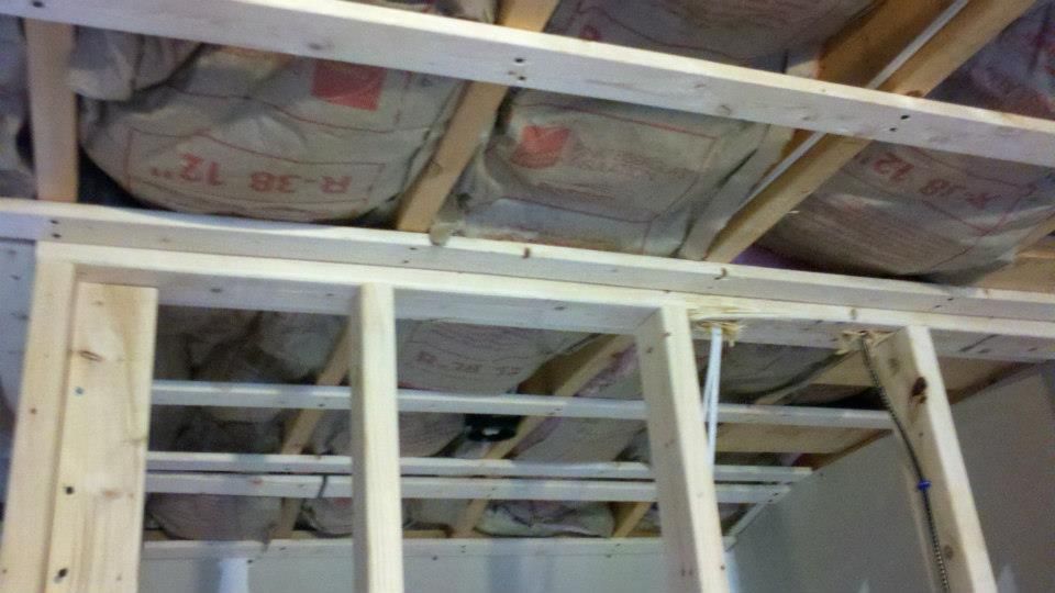 Plywood installed on a sloped roof next to a gutter; scaffolding visible below.