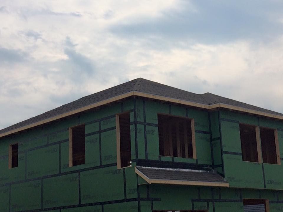 Tan house with black roof and dormer window.