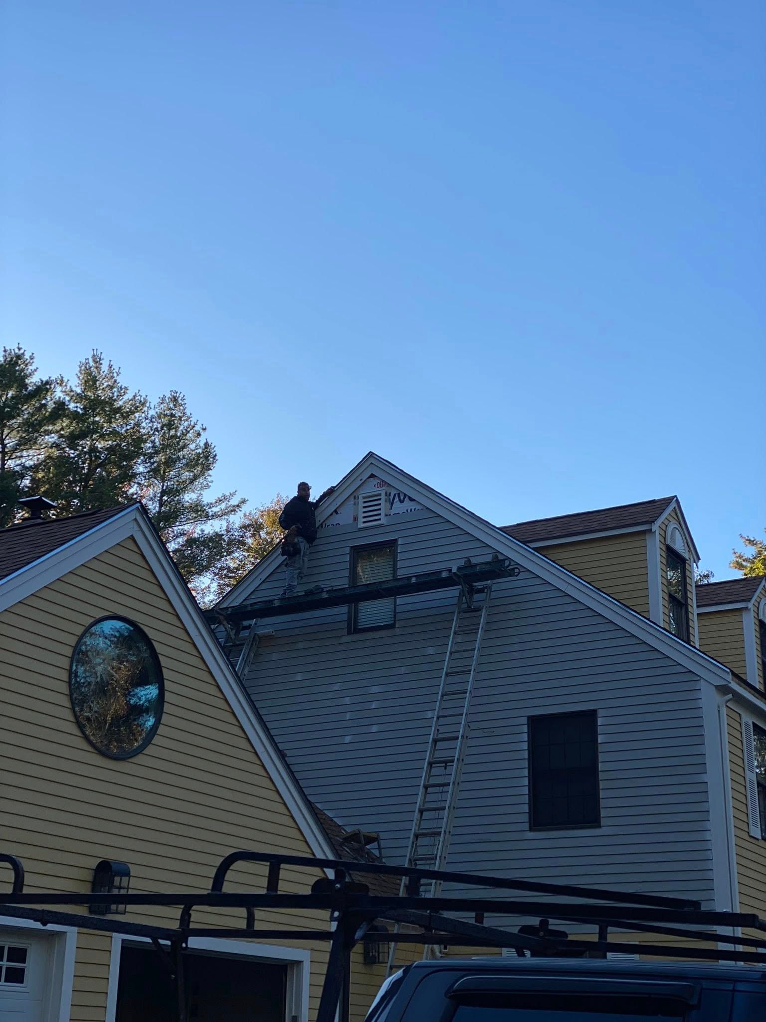 Cottage with screened-in porch, dark roof, and brick chimney under a clear blue sky.