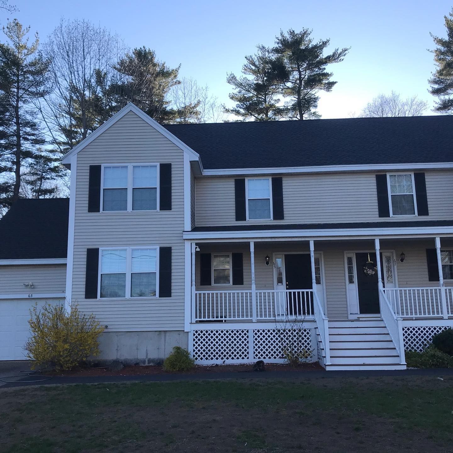 Two-story beige house with black shutters, porch, and white trim. 