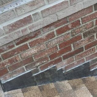 Brick wall with roofing shingles and flashing.
