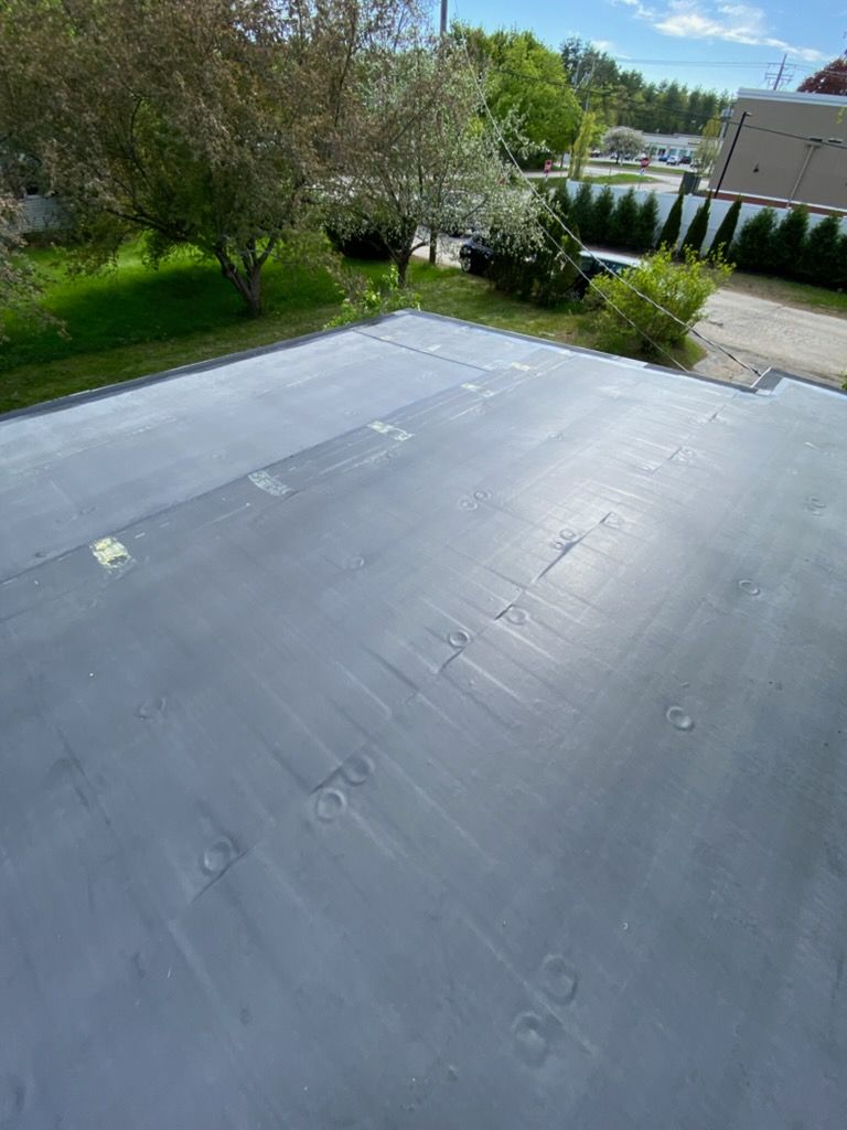 Rooftop with corrugated metal and wooden trim, overlooking trees under a blue sky