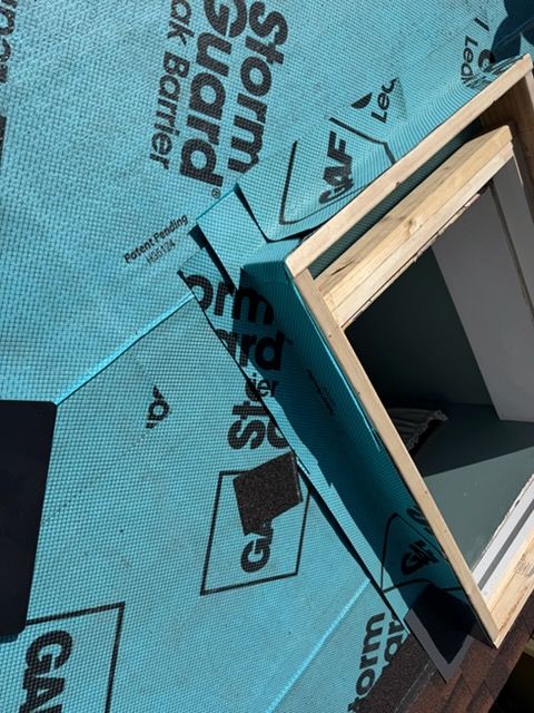 Blue roofing underlayment around a skylight opening on a slanted roof