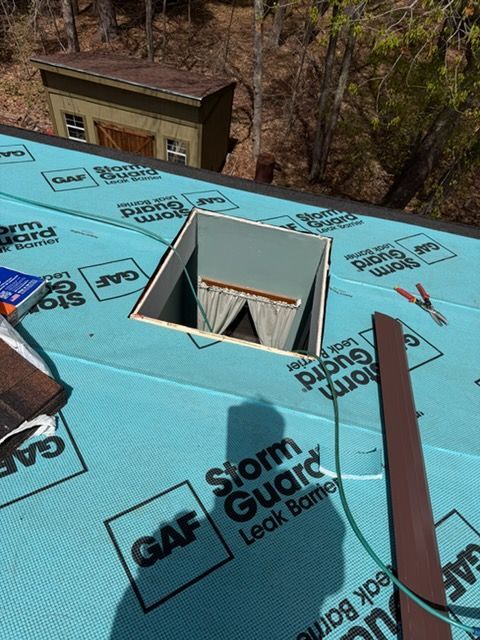 Blue roof under construction with a square skylight opening and roofing materials around it