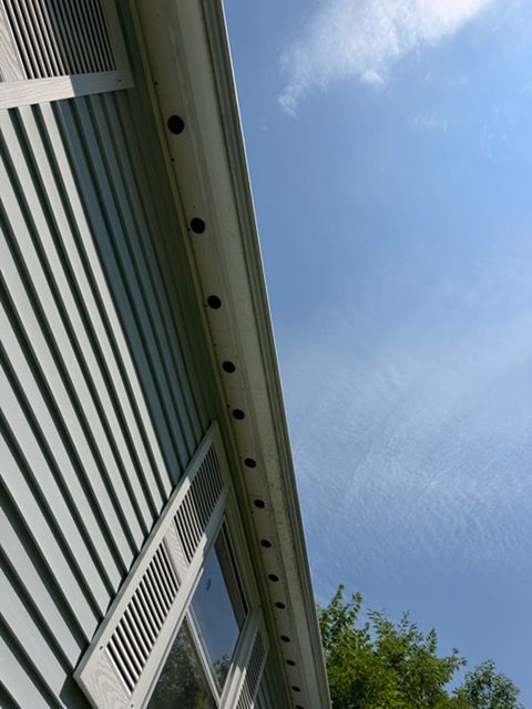 House siding with windows and roof eaves against a blue sky, viewed from below