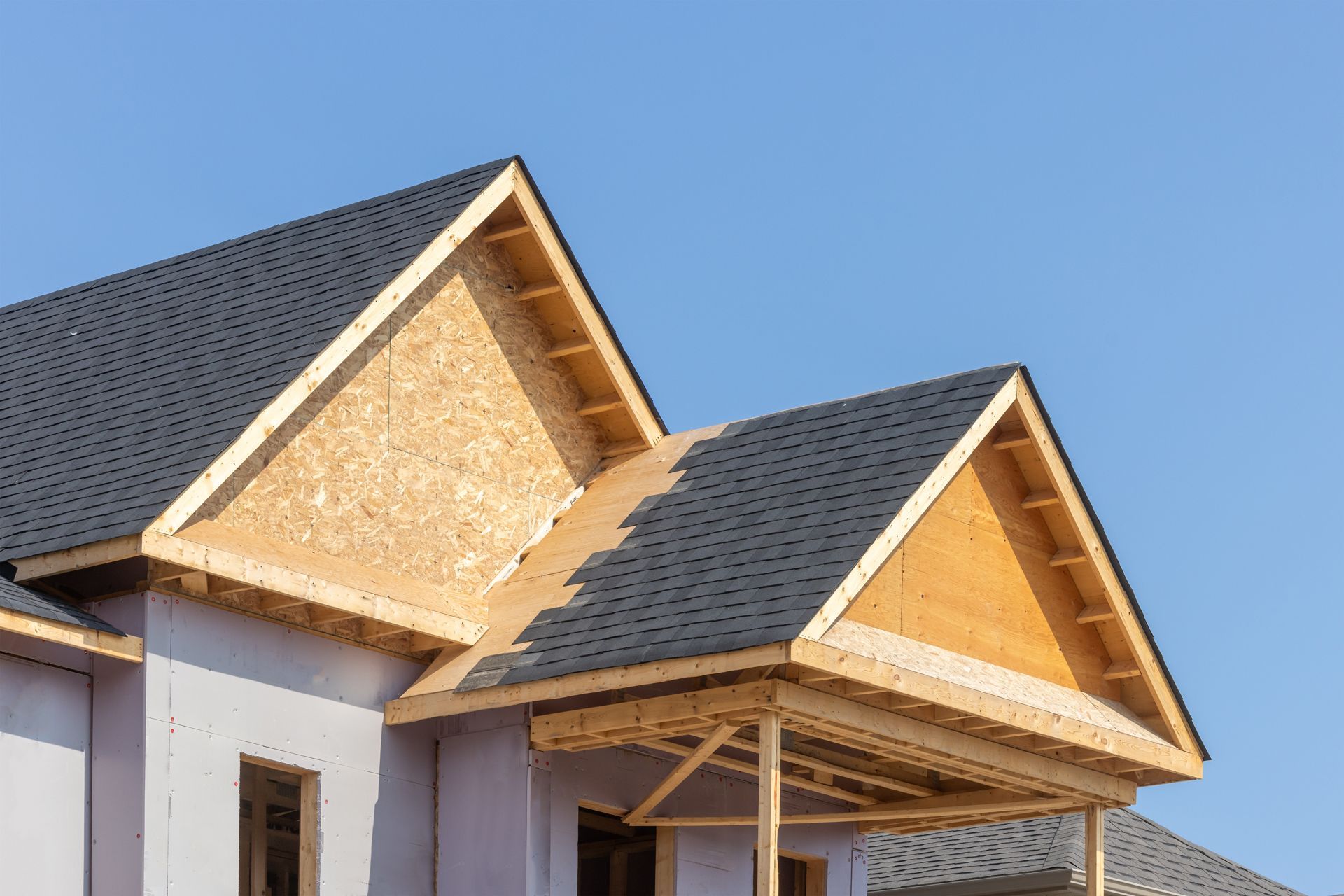 New house roof under construction with exposed wood framing and gray shingles
