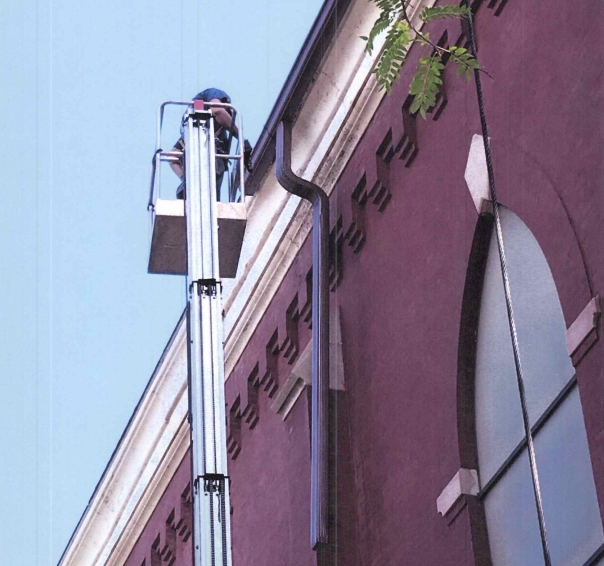 Dark gray gutters and downspout on a white house, against a teal sky. Dark gray gutters and downspout on a white house, against a teal sky.