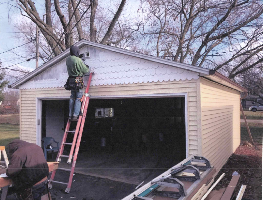 Interior view of attic insulation. Yellow fiberglass batts between wooden studs. A ladder and small window are present. Interior view of attic insulation. Yellow fiberglass batts between wooden studs. A ladder and small window are present.