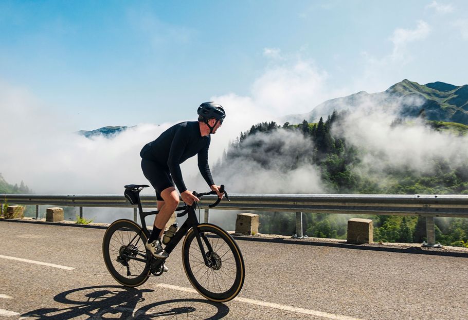 Un uomo sta andando in bicicletta su una strada con le montagne sullo sfondo.