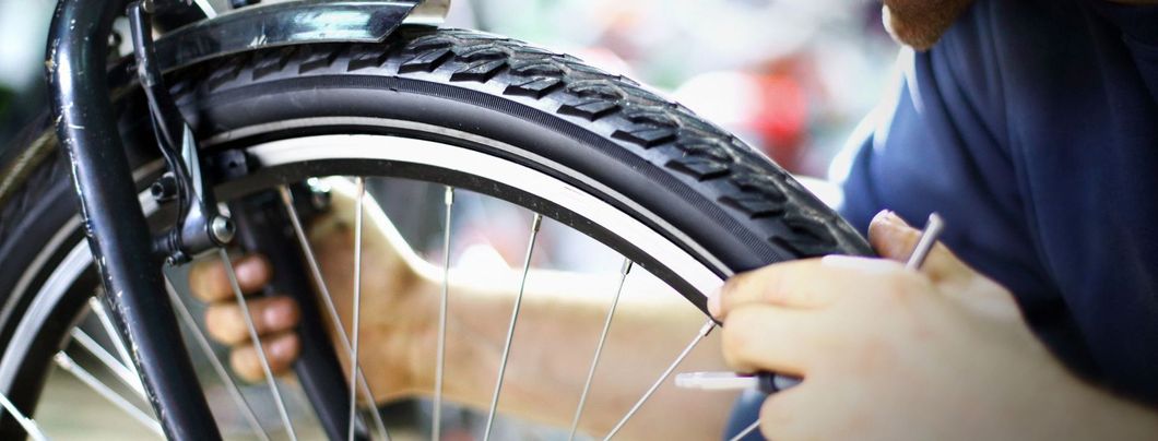 Una persona sta riparando una gomma di bicicletta con una chiave inglese.