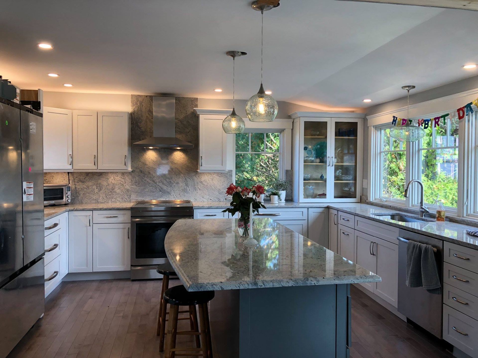 Bright modern kitchen with white cabinets, gray island, pendant lights, and a flower centerpiece