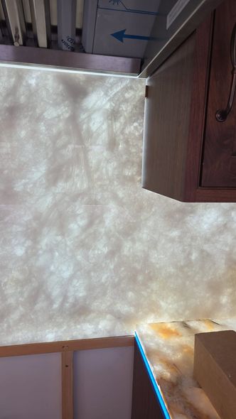 Upward view of a bright, textured ceiling with wood cabinets at the edges and a blue arrow sign near the top