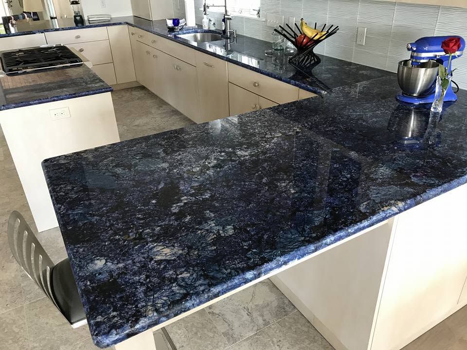 Modern kitchen with dark granite island countertop and beige cabinets, with a stand mixer on the right.