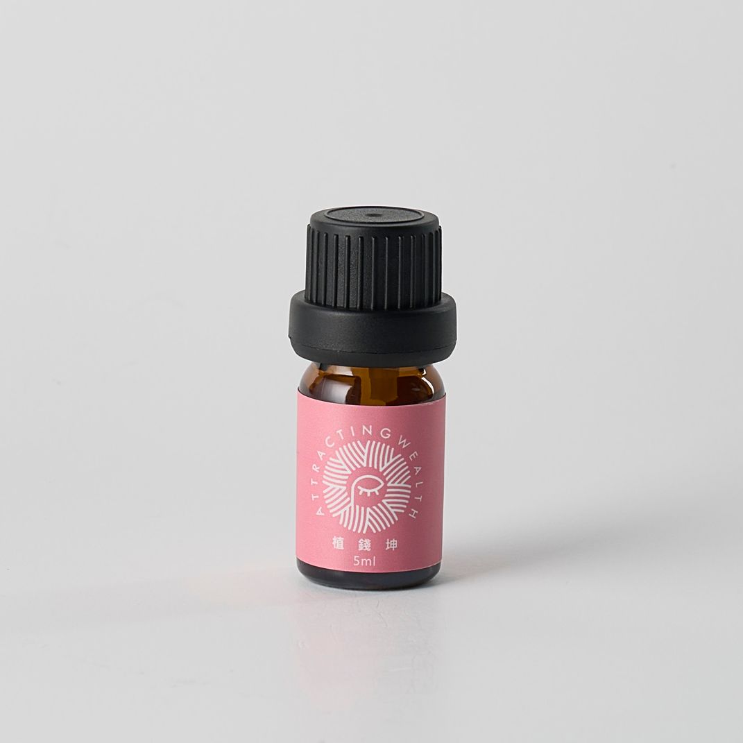 白色背景上的小型棕色精油瓶，粉紅色標籤，黑色瓶蓋。