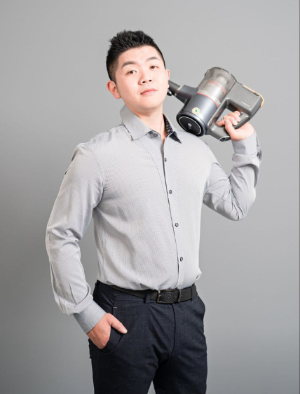 一名身穿襯衫的男子肩扛無線吸塵器,背景為灰色。