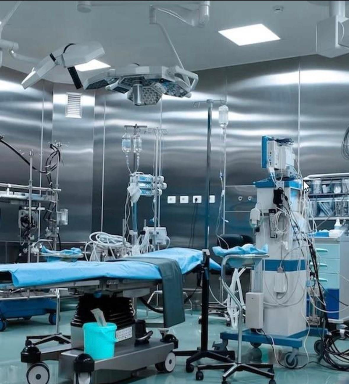 A modern surgical operating room featuring a patient table, medical equipment, and bright, metallic wall panels.