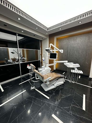 A modern dental operatory featuring a beige patient chair, dental equipment, and dark marble flooring in a sleek room.