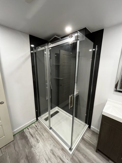 Une cabine de douche rectangulaire avec cadre métallique et parois en verre transparent, située dans une salle de bain modern