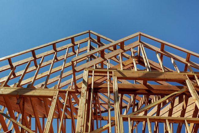 Ossature bois d'une maison en construction sur fond de ciel bleu clair