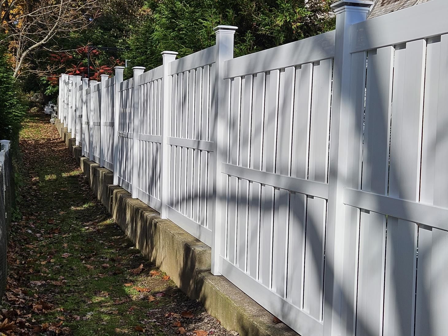 A wooden fence surrounds a lush green yard in front of a house.
