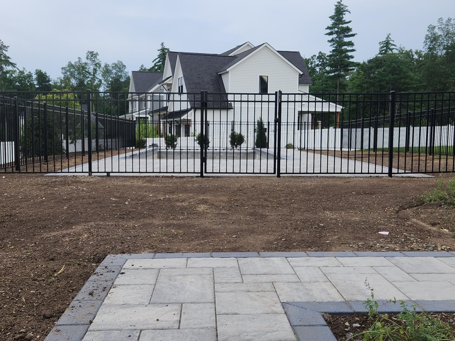 A fence made of wood and bricks surrounds a garden.