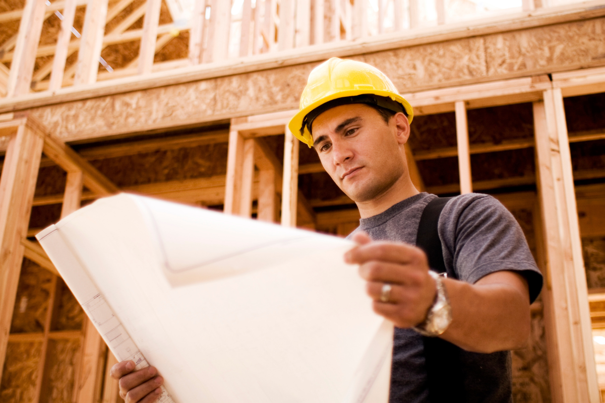 Construction worker looking at floor plans for new build