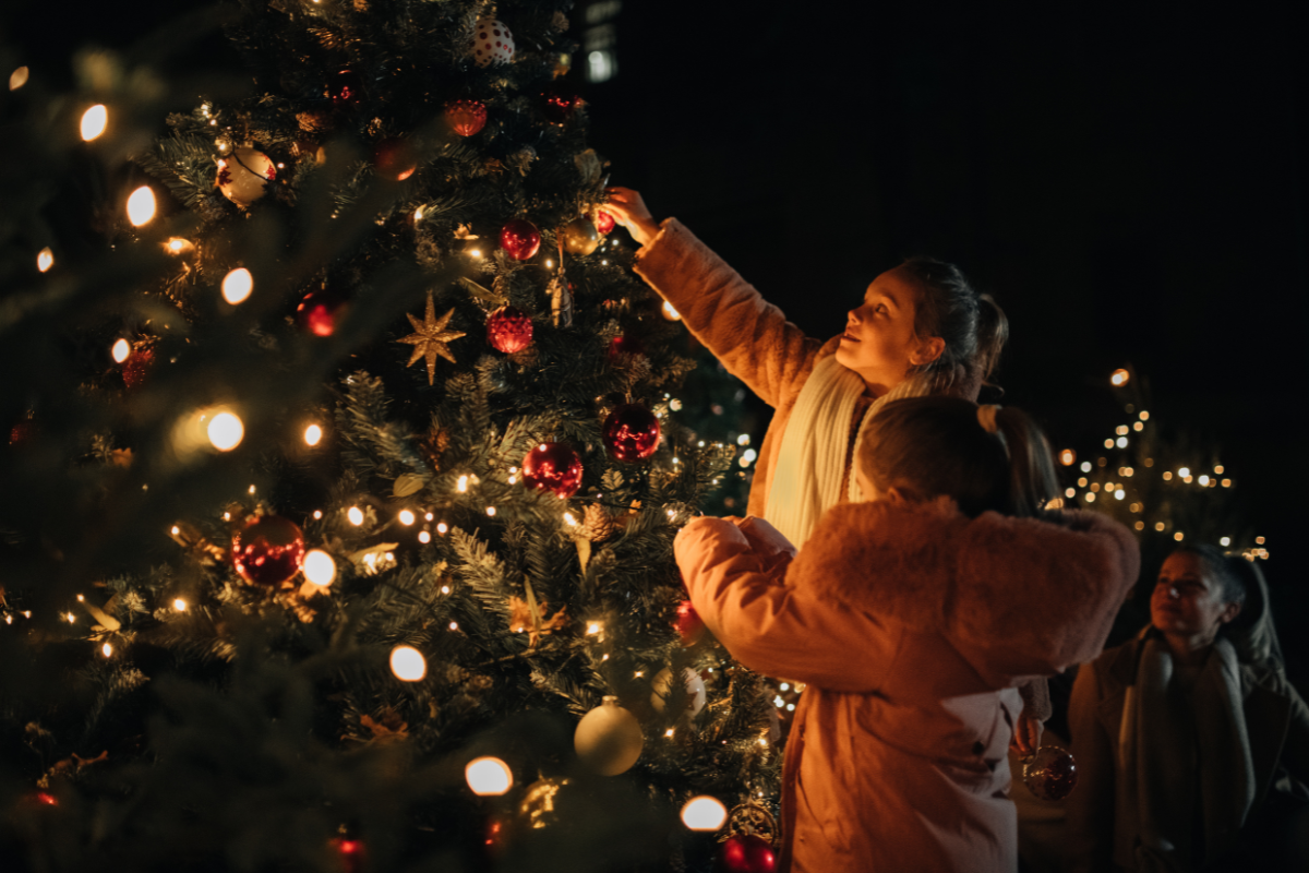 A group of people decorating a christmas tree at night