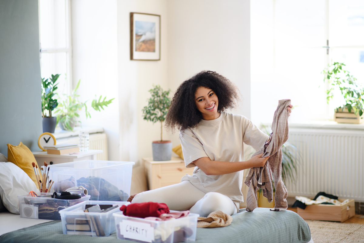 Girl sitting on floor packing clothing into boxes