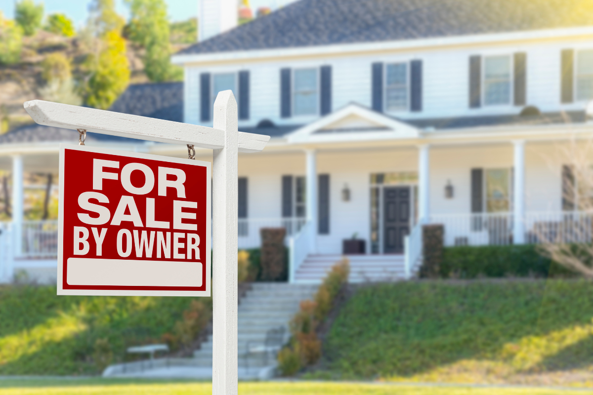 A for sale by owner sign in front of a house