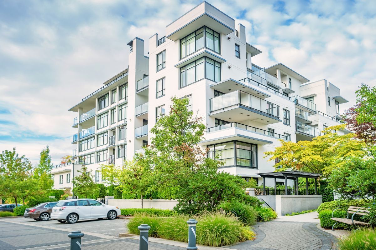 A large white apartment building with cars parked in front of it