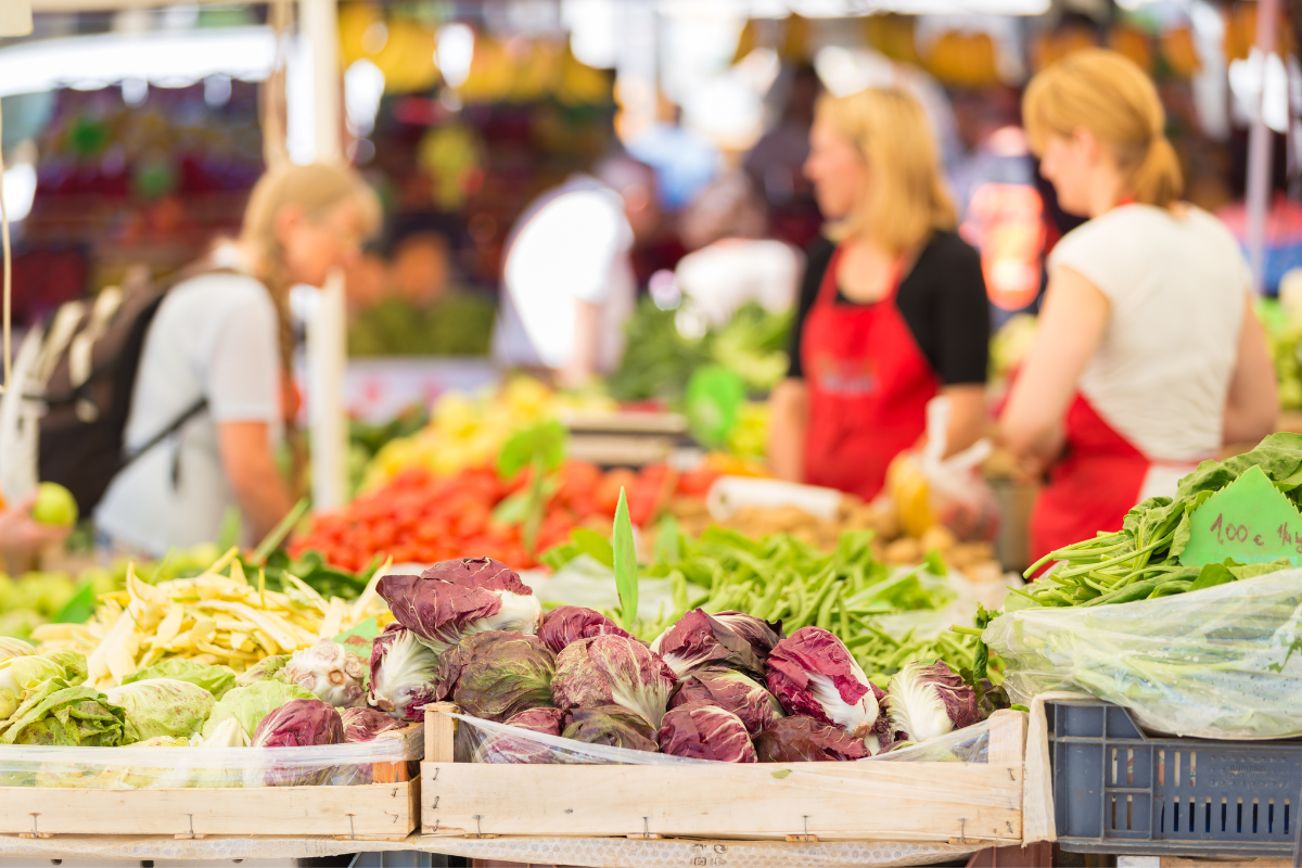 A woman in an apron is selling vegetables at a market