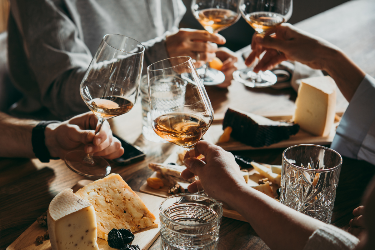 A group of people are sitting at a table toasting with wine glasses