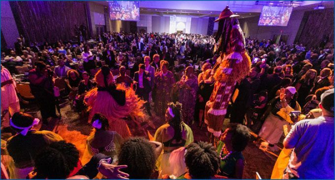 A large crowd of people are dancing in a large room