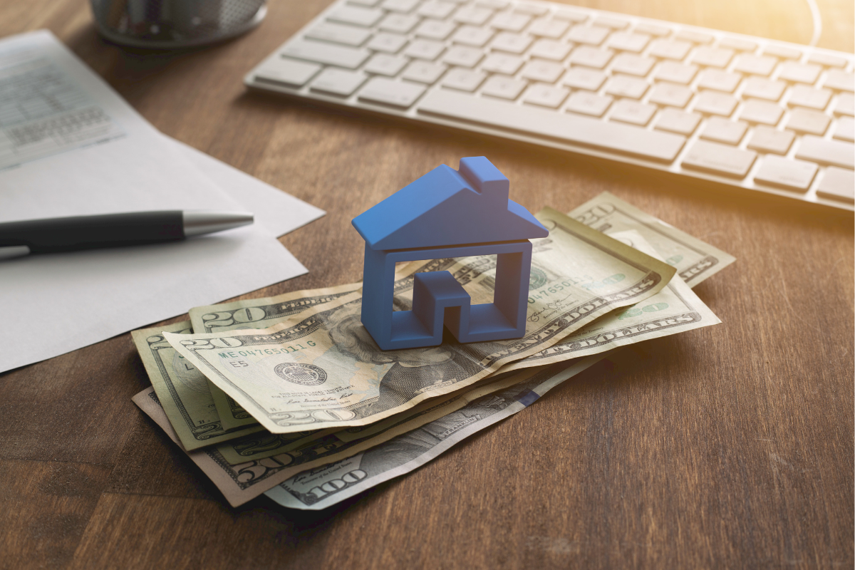 A blue house is sitting on top of a pile of money