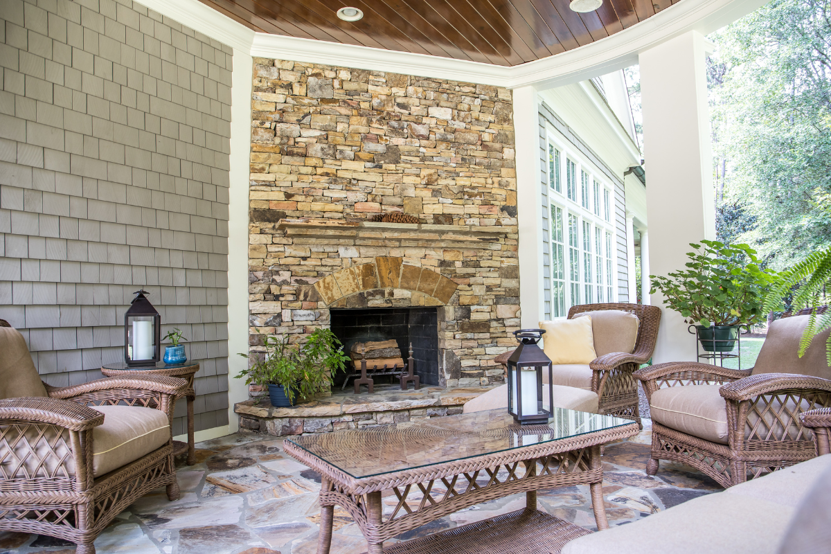 A patio with wicker furniture and a stone fireplace